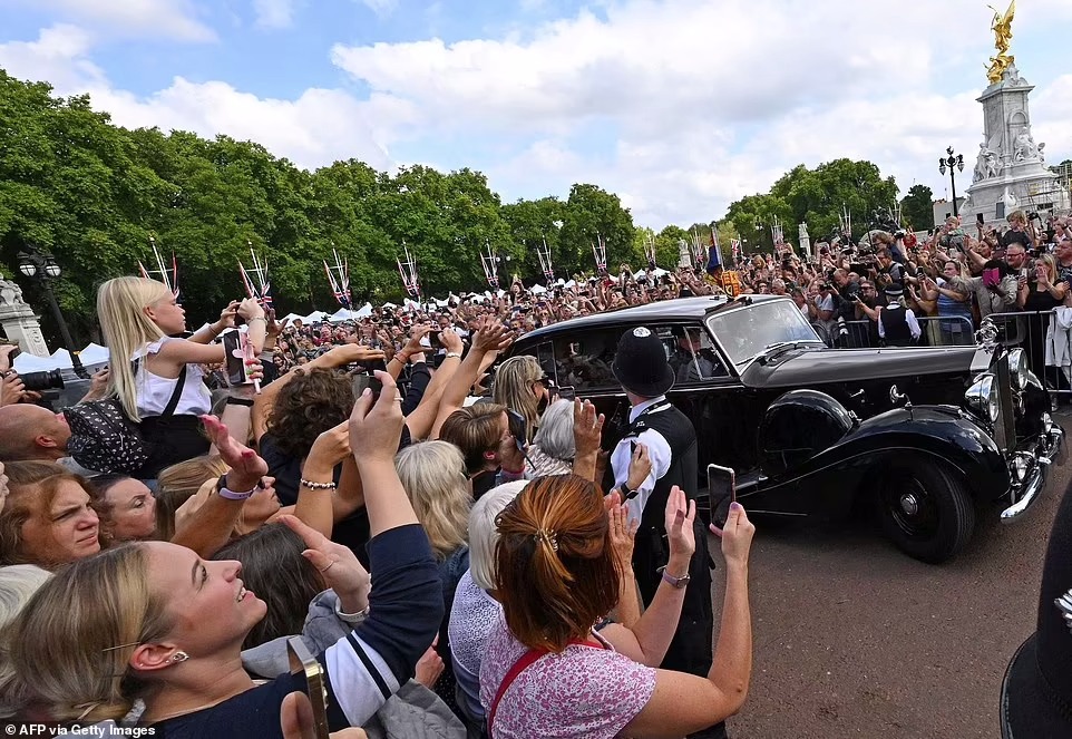 Members of the public gather to watch King Charles III arrive by car at Buckingham Palace