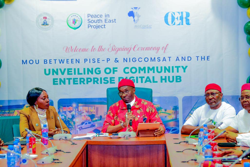 Managing director of the Nigerian Communications Satellite (NIGCOMSAT) Jane Nkechi Egerton-Idehen (l) and  Deputy Speaker of the House of Representatives, Rt Hon. Benjamin Kalu (r) signing MoU between PISE-P and NIGCOMSAT for a community enterprise hub, at the National Assembly Abuja, as Lawmakers and PISE-P members look on